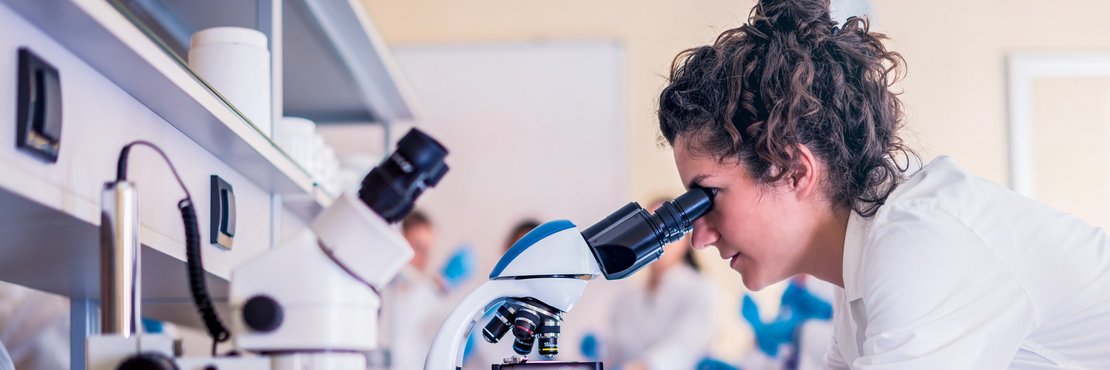 Weibliche Person schaut durch ein Mikroskop