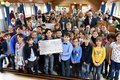 Eine Schulklasse mit symbolischem Scheck