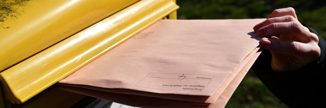 Briefe werden in einen öffentlichen Postkasten geworfen.