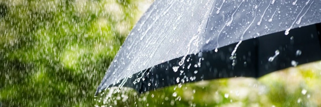 Symbolbild: Starker Regen prasselt auf Regenschirm