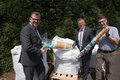Drei Personen mit Behältern gefüllt mit Plastikdeckeln