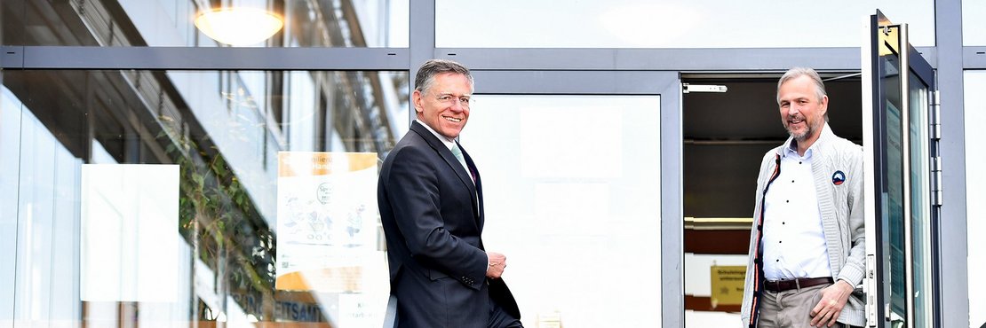 Landrat Hans-Jürgen Petrauschke und Kreisdirektor Dirk Brügge stehen an einem Eingang zu einem Verwaltungsgebäude.