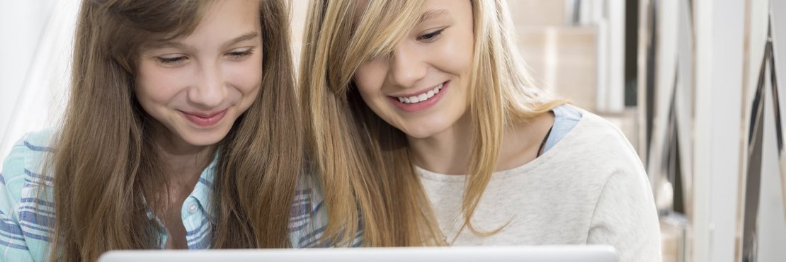 Zwei junge Frauen schauen auf ein Laptop