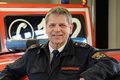 Kreisbrandmeister Norbert Lange vor einem Feuerwehrauto mit Blaulicht