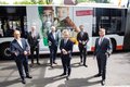 Die 6 Herren stehen vor einem Linienbus und halten Ihre Smartphones in den Händen