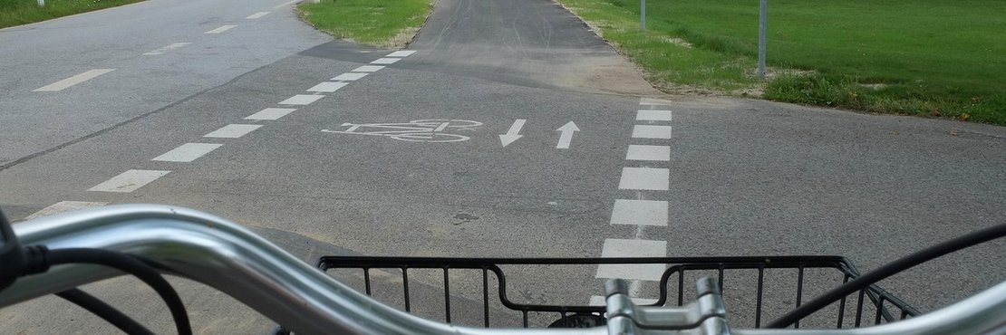 Blick über Fahrradlenker auf Radweg