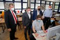 4 Herren stehen hinter 2 Schülern, die am Computer arbeiten