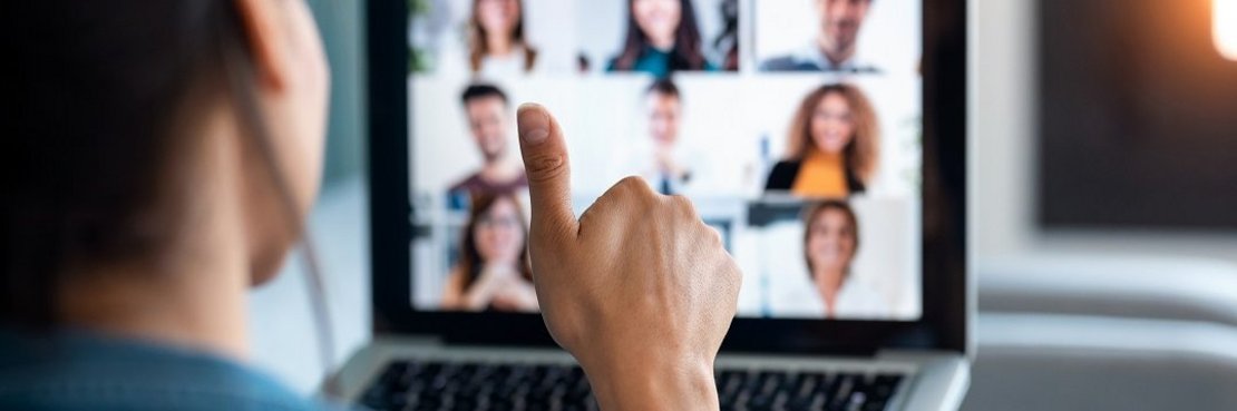 Eine Person sitzt vor einem Laptop mit Web-Konferenz