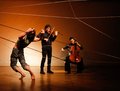 Geige, Cello und Tänzer zwischen gespannten Seilen auf der Bühne