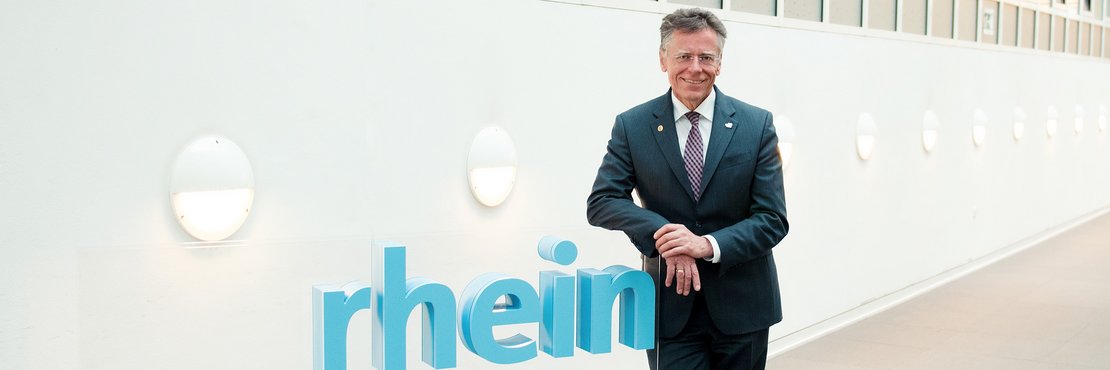 Landrat Hans-Jürgen Petrauschke lehnt an einem 3-D-Logo des Rhein-Kreises Neuss
