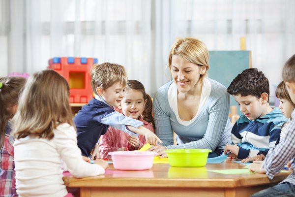 dekorativ, Erzieherin oder Tagemutter mit Kindern am Tisch