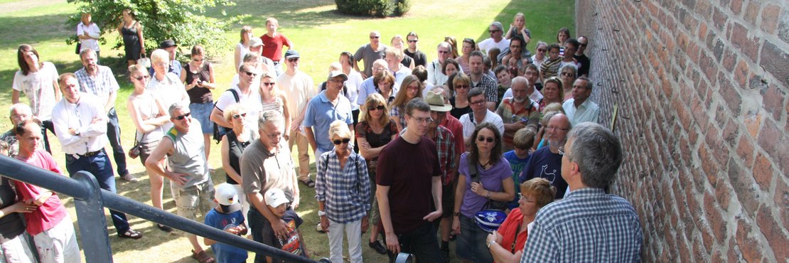 Gruppe bei Führung an Treppe der historischen Burgmauer