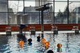 Orangene Wasserbälle auf der Wasseroberfläche in einem Hallenbad.