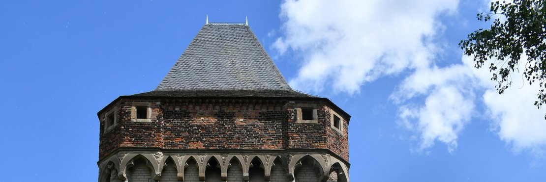 Turm einer Burg vor blauem Himmel.