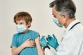 Ein Kind wird von einem Arzt mit einer Spritze geimpft.