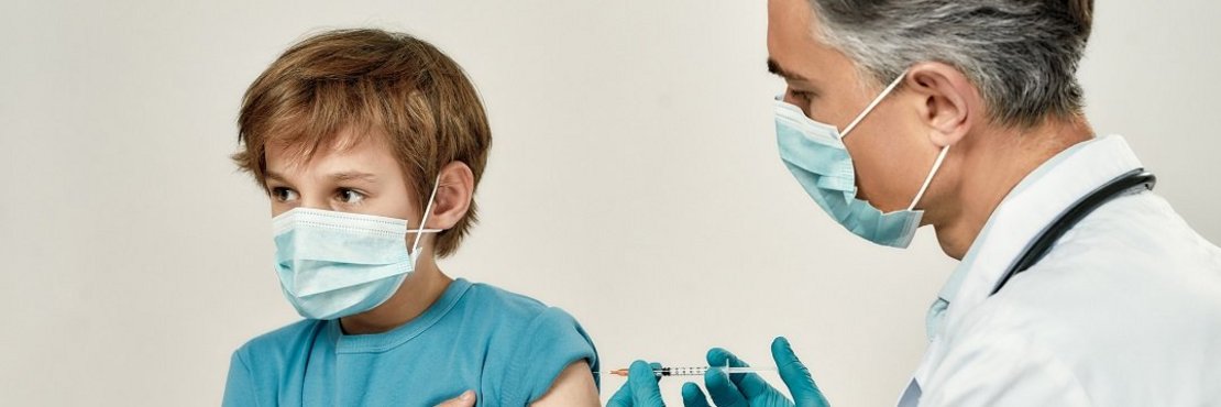 Ein Kind wird von einem Arzt mit einer Spritze geimpft.