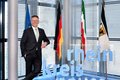 Landrat Hans-Jürgen Petrauschke  lehnt an einem 3-D-Logo des Rhein-Kreises Neuss