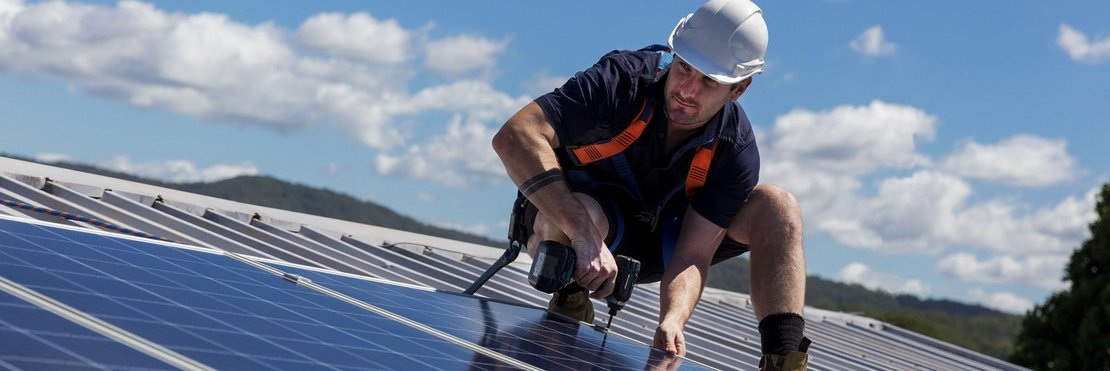 Handwerker montiert Solarmodule auf Dach