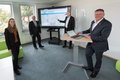 Die genannten Personen stehen vor einem großen Monitor, der das Gewerbeflächenportal zeigt
