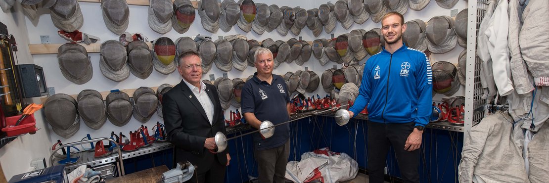 Landrat Hans-Jürgen Petrauschke, Olaf Kawald und Benedikt Wagner in einem Materialraum für Säbelfechter.