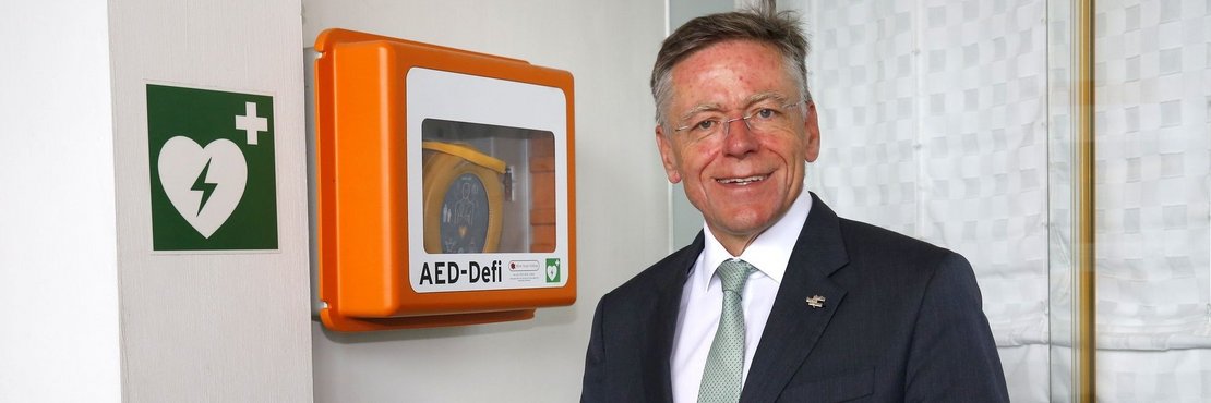 Landrat Hans-Jürgen Petrauschke hält einen Defibrillator in den Händen
