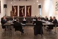 Männer und Frauen sitzen an Tischen in Saal