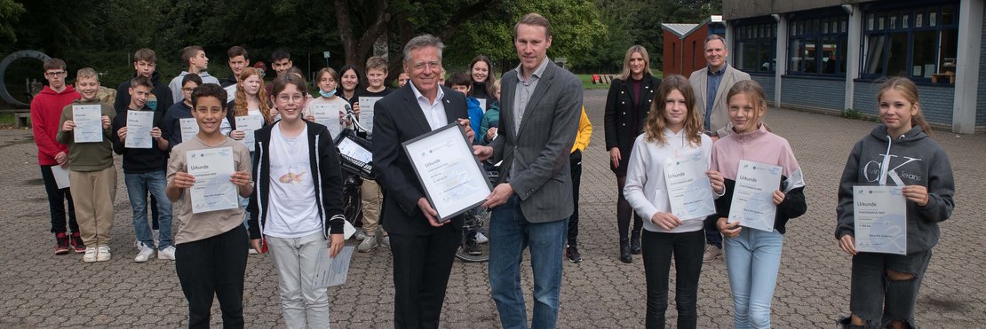 Gruppenfoto auf Schulhof: Landrat Hans-Jürgen Petrauschke überreichte Urkunden an Lehrer Timotheus und Schülerinnen und Schülern des Pascal-Gymnasiums.