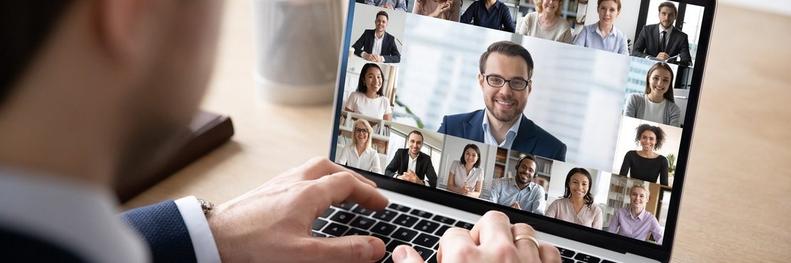 Mann sitzt vor Laptop in Online-Konferenz