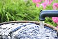 Wasser läuft aus einem Hahn in eine Tonne