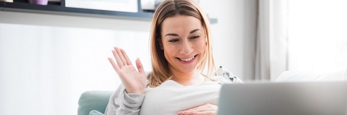 Eine schwangere Frau vor einem Laptop