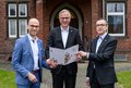 Foto von Kreisdirektor Dirk Brügge bei der Überreichung des Zuwendungsbescheides für das Projekt „Ankommen im Rhein-Kreis Neuss“ an die TZG-Geschäftsführer Benjamin Josephs und Raimund Franzen.