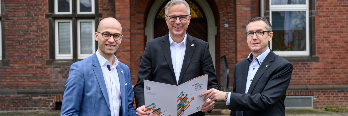 Foto von Kreisdirektor Dirk Brügge bei der Überreichung des Zuwendungsbescheides für das Projekt „Ankommen im Rhein-Kreis Neuss“ an die TZG-Geschäftsführer Benjamin Josephs und Raimund Franzen.