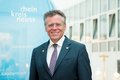 Männliche Person vor einer blauen Fahne mit weißem Kreislogo