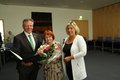 Drei Personen - die mittlere Person hält einen Blumenstrauß