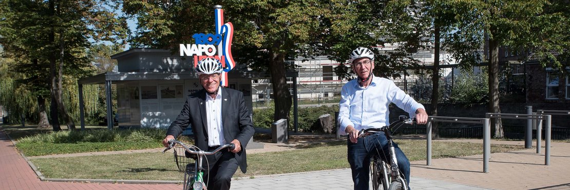 Die beiden Herren steigen auf Ihre Fahrräder. Sie stehen vor dem historischen Wasserkreuz am Nordkanal