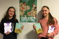 Zwei weibliche Personen halten Bücher in den Händen und je eine Urkunde