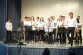 Musikschüler und Lehrer stehen mit Instrumenten auf einer Bühne.