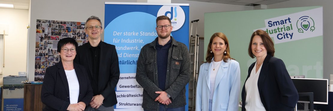 Drei Frauen und zwei Männer stehen neben einenm Banner der Stadt Dormagen.