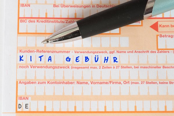 dekorativ, Überweisungsschein ausgefüllt mit "Kita Gebühr" und Kugelschreiber