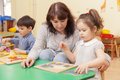Eine Frau spielt mit zwei Kleinkindern an einem Tisch