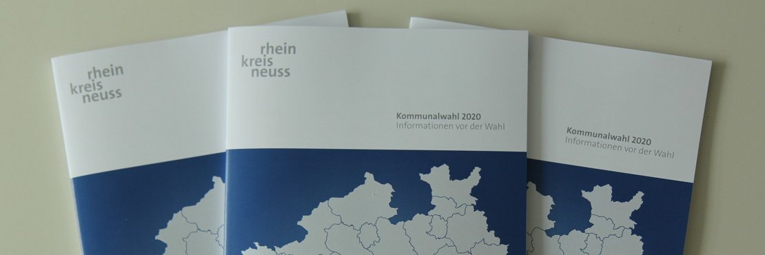Drei Broschüren liegen auf dem Tisch. Darauf zu sehen der Rhein-Kreis Neuss auf einer stilisierten Karte von NRW