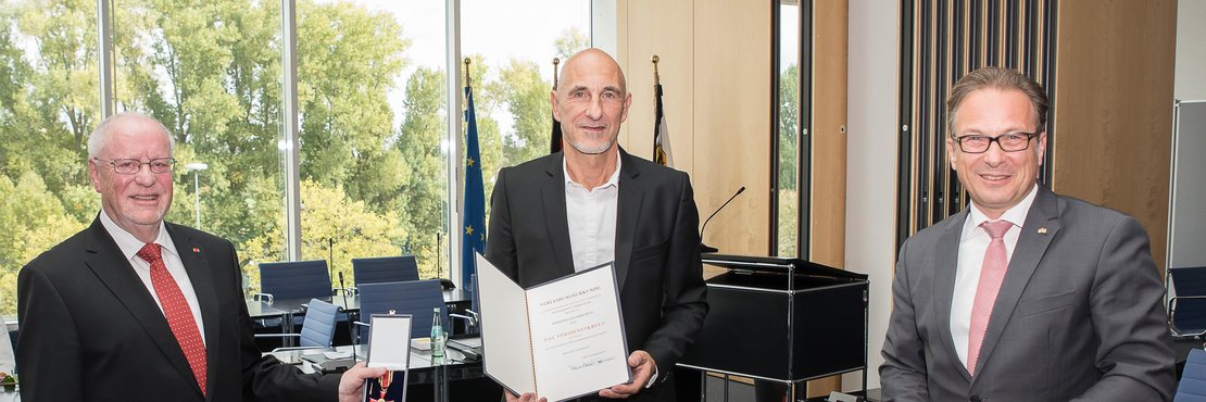 Der Stellvertretende Landrat Host Fischer überreicht Roland Debschütz im Beisein des Neusser Bürgermeisters Reiner Breuer das Bundesverdienstkreuz.