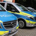 Das Bild zeigt drei Polizeiautos, die nebeneinander auf einem gepflasterten Parkplatz stehen.  Im Vordergrund steht ein blauer Mercedes-Benz Vito mit gelben Streifen und dem Wort „POLIZEI“ auf der Motorhaube.  Hinter diesem befinden sich zwei weitere Polizeifahrzeuge, eines davon ebenfalls ein größerer Van, das andere ein Ford.  Alle Fahrzeuge tragen die typische blau-gelbe Polizeifarbung. © Polizei Rhein-Kreis Neuss
