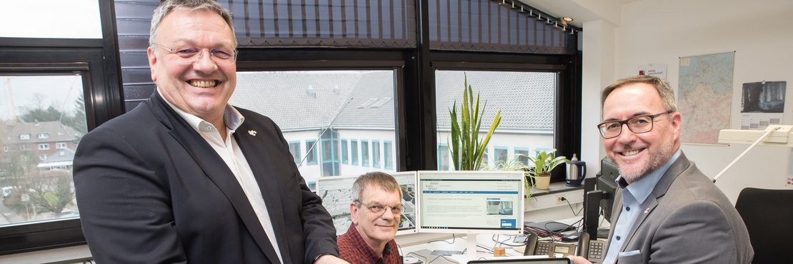 Harald Vieten, Peter Koenen und Michael Fielenbach vor einem Computer mit Mobiltelefon und Tablet in den Händen