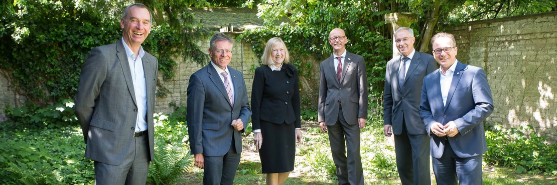 Stefan Stelten, Landrat Hans-Jürgen Petrauschke, Notarin Dr. Christine von Hertzberg, Harald Zillikens, Ingolf Graul und Reiner Breuer stehen mit Abstand auf einer Wiese