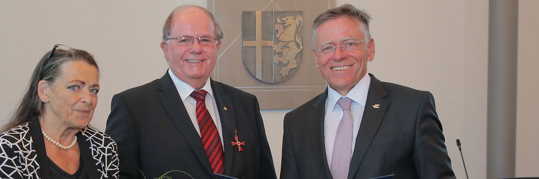 Landrat Hans-Jürgen Petrauschke steht mit Theo Thissen und Gattin Heidi (mit Blumenstrauß) im Kreissitzungssaal in Grevenbroich