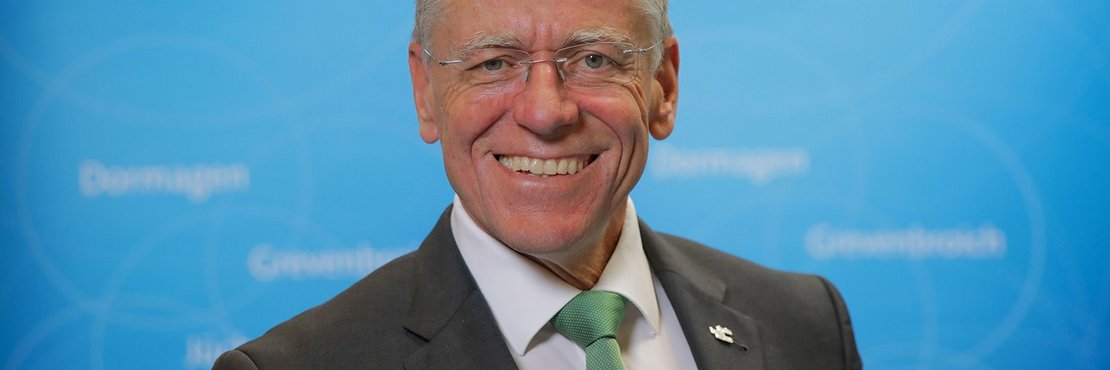 Hans-Jürgen Petrauschke lächelnd vor blauer Fotowand