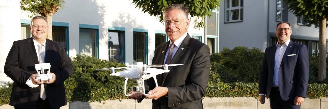 Landrat Hans-Jürgen Petrauschke mit einer Drohne in seinen Händen, Herr Fielenbach Amtsleiter Katasteramt mit einer Drohnen-Fernbedienung und Dezernent Herr Vieten.