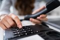 Ein Mensch hat einen Telefonhörer in der Hand und tippt auf das Bedienfeld
