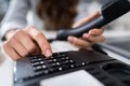 Ein Mensch hat einen Telefonhörer in der Hand und tippt auf das Bedienfeld